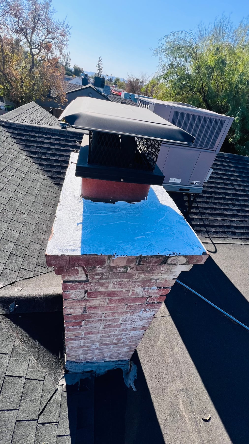 Deteriorating brick chimney with crumbling mortar and spalling on rooftop needing repair