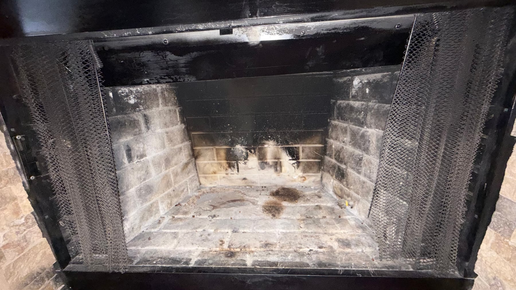 Dirty firebox interior with soot-covered firebrick walls and ash deposits needing cleaning or repair