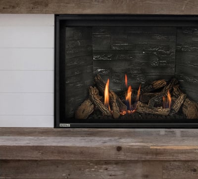 Modern gas fireplace insert with log set in stacked stone wall surround