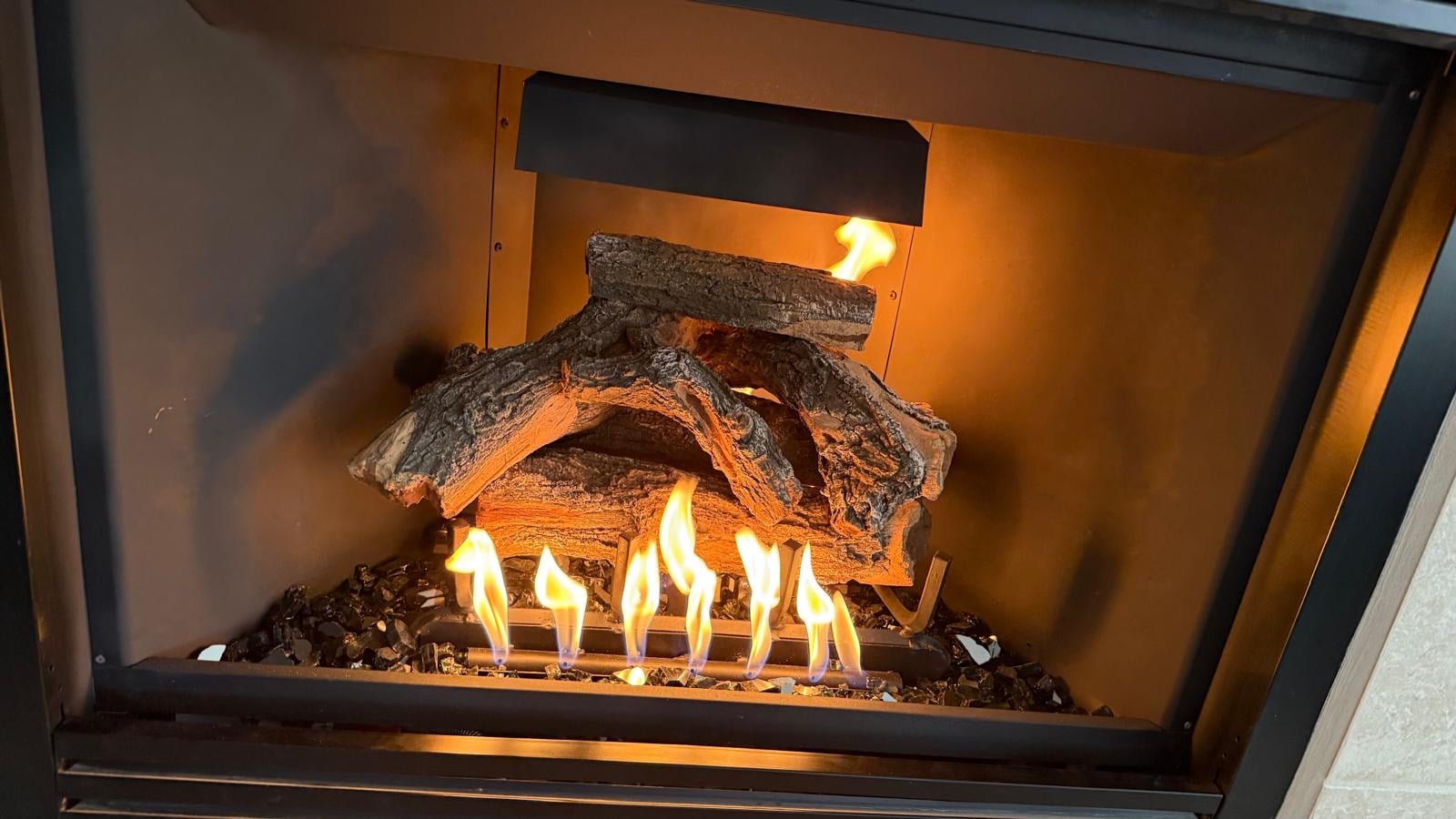Gas log set with active flames burning inside a modern fireplace insert in Arizona